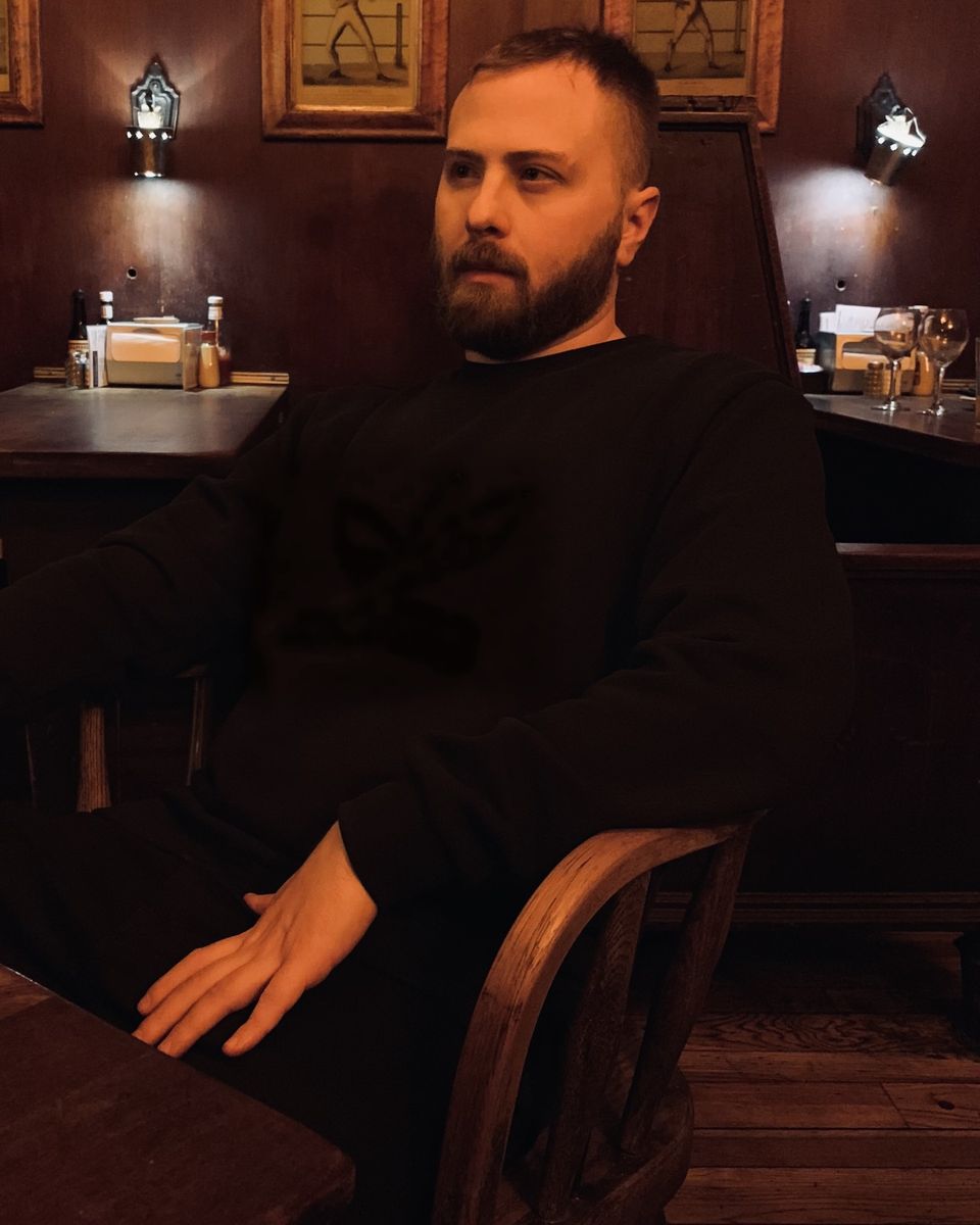 TakTrack with a full beard, seated at a restaurant table.