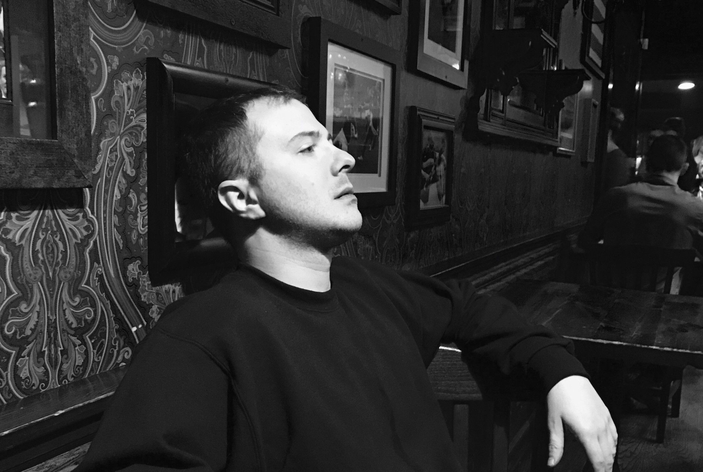 Black-and-white photo of TakTrack leaning back in a bar booth.