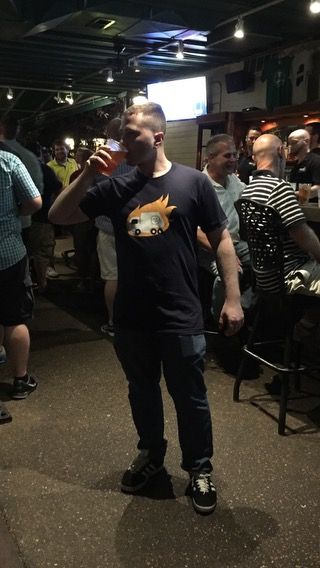 TakTrack drinking from a cup while standing in a busy bar.
